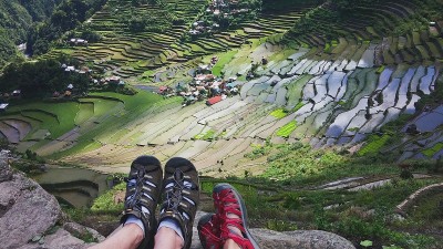 两名徒步旅行者坐在山顶上欣赏菲律宾巴塔德村梯田的美丽景色