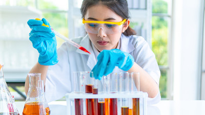 女研究员白袍教授用桌上的科研设备准备测试化学液体。与浓度。与背景室内白色实验室。