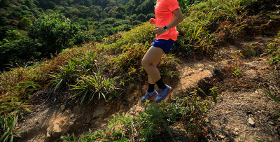 女子超级马拉松运动员在热带森林的山坡上跑下坡