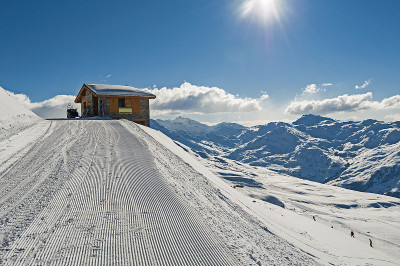 全景横跨积雪覆盖的山坡上的高山与小茅屋