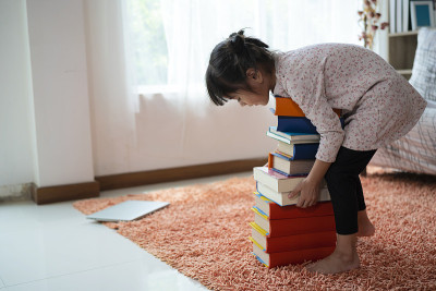 亚洲小孩小女孩阅读完后在橱柜里收集书籍