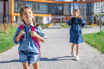 小女孩，小学生背着书包离开学校。