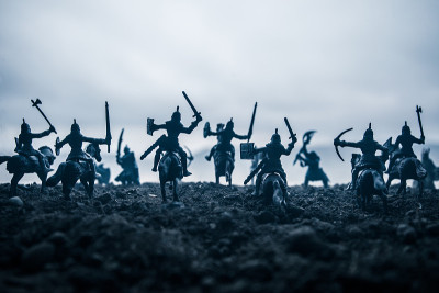 有骑兵和步兵的中世纪战斗场景。剪影的人物作为单独的对象，战斗之间的战士在日落雾蒙蒙的背景。有选择性的
