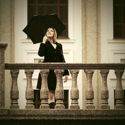 年轻时尚的女人拿着雨伞走在城市的街道上