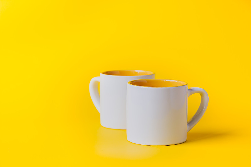 Empty coffee or tea white cup with yellow on yello