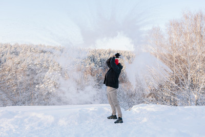 一个年轻人在白雪覆盖的森林里享受冬日