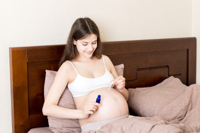 孕妇在腹部涂抹妊娠纹霜。怀孕，人与孕的观念。孕妇在腹部涂抹抗妊娠纹霜