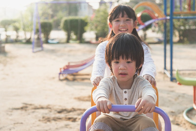 可爱的亚洲小孩在操场上玩跷跷板
