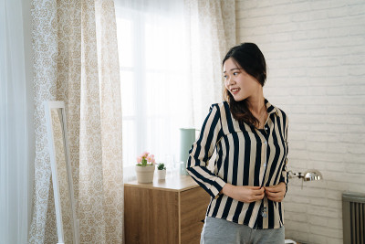 女工人在镜子前把衬衫扣子扣上