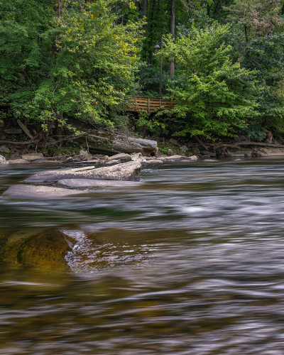A shallow river flows downstream beneath a wooden 