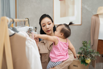 做一个职业妈妈是不容易的!年轻美丽的设计师在她的工作室工作，而站在她的宝贝女儿