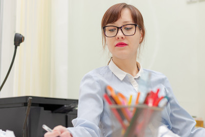 戴眼镜的漂亮女商人在办公室的工作台上签署文件