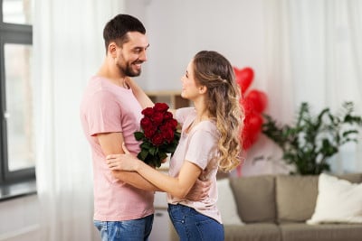 幸福的夫妇捧着一束鲜花拥抱在家里