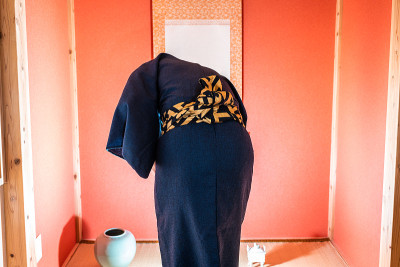 传统的日本房间有壁龛，壁龛上挂着卷轴，红色的和服上的男人在祈祷