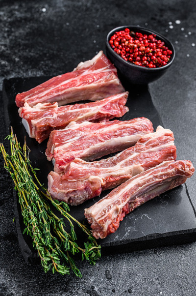 生小牛肉切成薄片，放在大理石板上。黑色背景。前视图。本空间