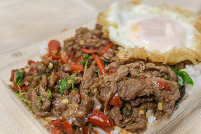 米饭配上炒牛肉，圣罗勒和鸡蛋，放在一个塑料盒里，这是泰国很受欢迎的街头小吃。