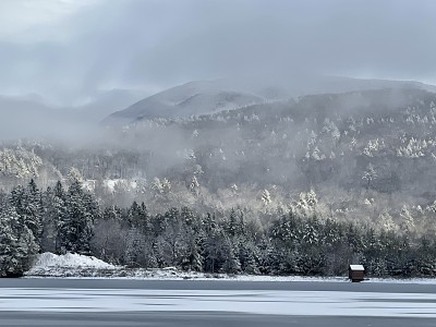 云覆盖着雪山和湖边的树木