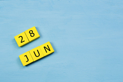 6月28日，黄色立方日历在蓝色木质表面与复制空间