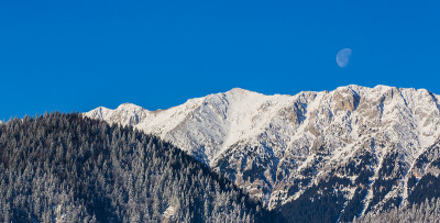 冬天的风景在山上，有白雪覆盖的山峰和落日的月亮