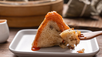 粽子吃——年轻的亚洲妇女在家里的木桌上吃中国传统食物庆祝端午节。