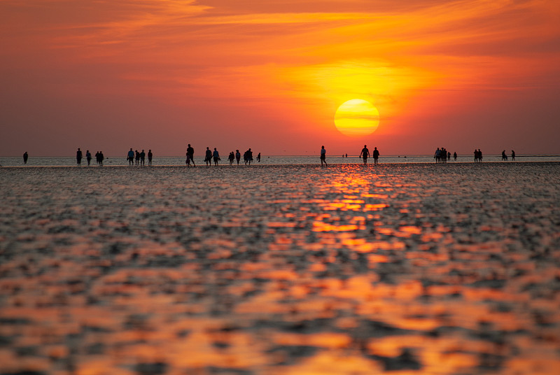 海滩上人们的剪影和日落前瓦特的全景图。