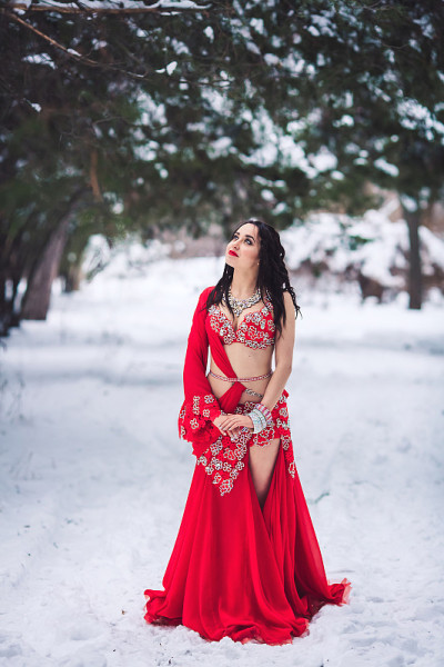 美丽的年轻女孩跳舞肚皮舞在冬天在一个公园的雪地上。