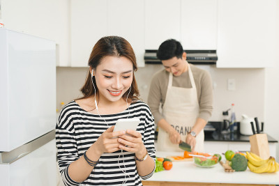亚洲妇女拿着手机在厨房里等待食物