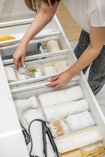 年轻女子整理浴室的收纳，在抽屉里展示化妆品和盥洗用品