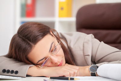 年轻疲惫的女人在办公室闭眼睡觉，睡眠剥夺和充满压力的生活观念