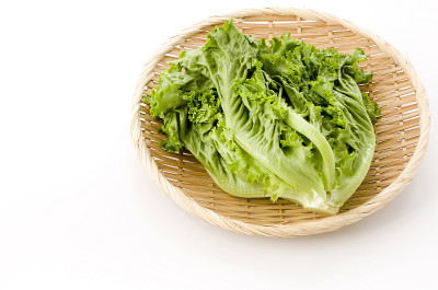 白底竹制滤锅上的新鲜绿叶生菜