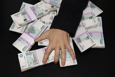 男人的手伸向一叠钱。一百万卢布放在黑色的桌子上。财富的概念，成功，贪婪和腐败，对金钱的欲望