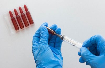 俯视图:妇女手戴医用手套，往注射用维生素B组注射器桶中填充