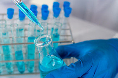 生物化学实验室研究，科学家或医务人员在实验室工作的玻璃设备上，穿着实验室大褂，拿着带有彩色液体的使用