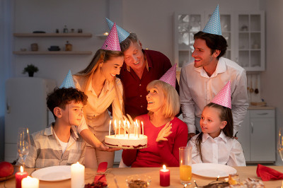 幸福的多代同堂的家庭举行生日聚会，在家里给老人送蜡烛生日蛋糕