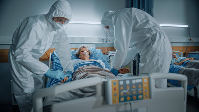 医院冠状病毒急诊科病房:医生、身穿工作服的医护人员、戴着口罩挽救一位躺在床上带氧气面罩的年长女性患者