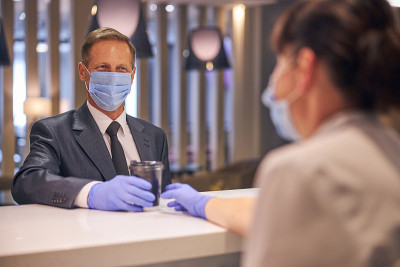 Smiling man in mask and gloves buying coffee