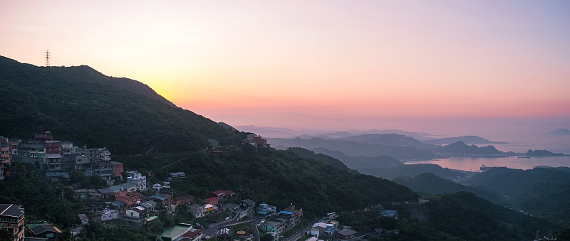 一幅海洋、山脉和美丽天空的景观全景图。T