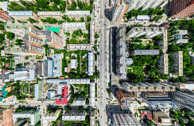 空中城市景观十字路口和道路，房屋，建筑物，公园和停车场。阳光明媚的夏日全景图