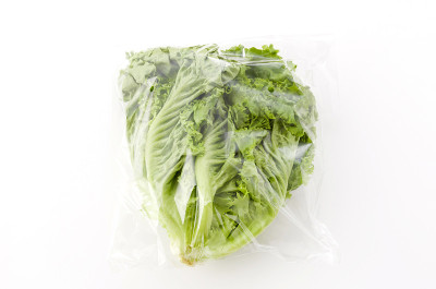 新鲜的绿叶生菜在塑料袋白色的背景