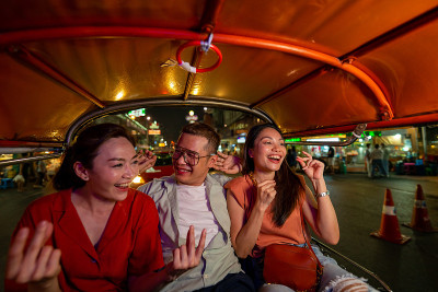 一群亚洲人朋友在曼谷乘坐嘟嘟出租车在晚上一起旅行。