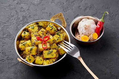 Aloo Methi在铜卡岱，碗在深色石板背景。Aloo Methi是用土豆、胡芦巴和香料做成的印度