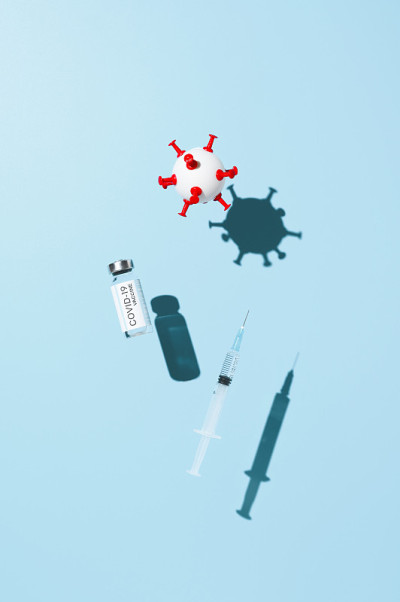 冠状病毒疫苗接种的概念。小瓶疫苗、医用注射器和悬浮在淡蓝色背景上的白色病毒球。俯视图