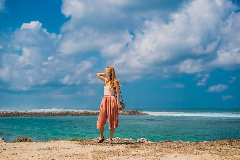 年轻女子旅行者在令人惊叹的美拉斯蒂海滩与绿松石水，印度尼西亚巴厘岛