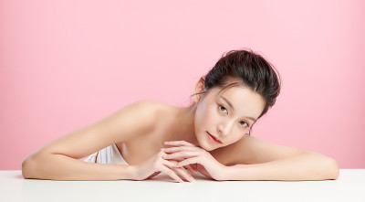 美丽年轻的亚洲女人与干净的新鲜皮肤在粉红色的背景，面部护理，面部治疗，美容和水疗中心，亚洲妇女肖像。
