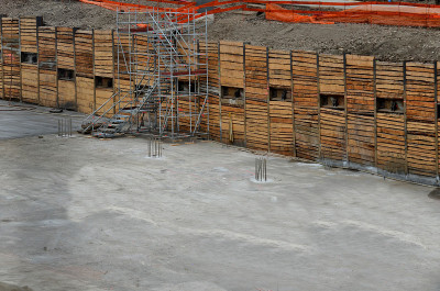 正在建造地下车库的建筑坑。木制挖掘板，并借助地锚固定墙壁，支撑岩石压力的横杆，脚手架制成的楼梯