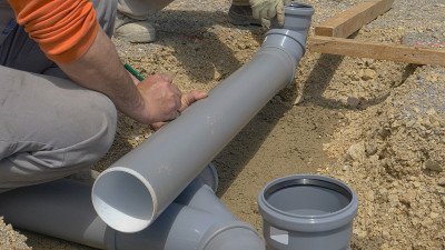 特写:不知名的建筑工人用铅笔在塑料污水管上做记号。