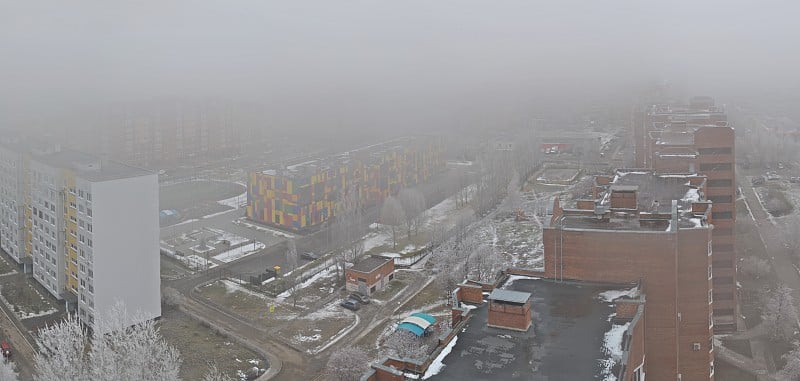 图里亚蒂市住宅区的冬季全景，笼罩在清晨的浓雾中。