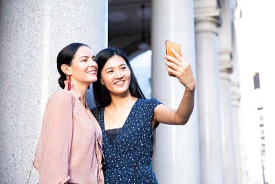快乐的中国亚洲女友在户外玩手机