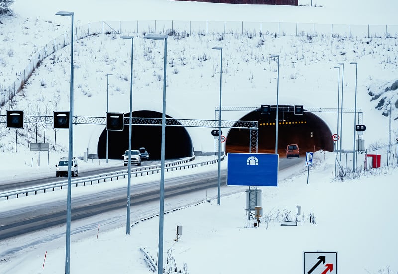 在暴风雪期间，汽车在被雪覆盖的公路和公路隧道上行驶。