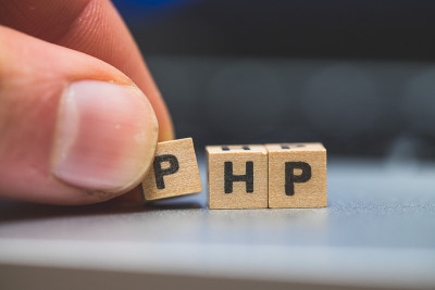 PHP编程网络语言:字母“PHP”的木制立方体躺在笔记本电脑上，概念